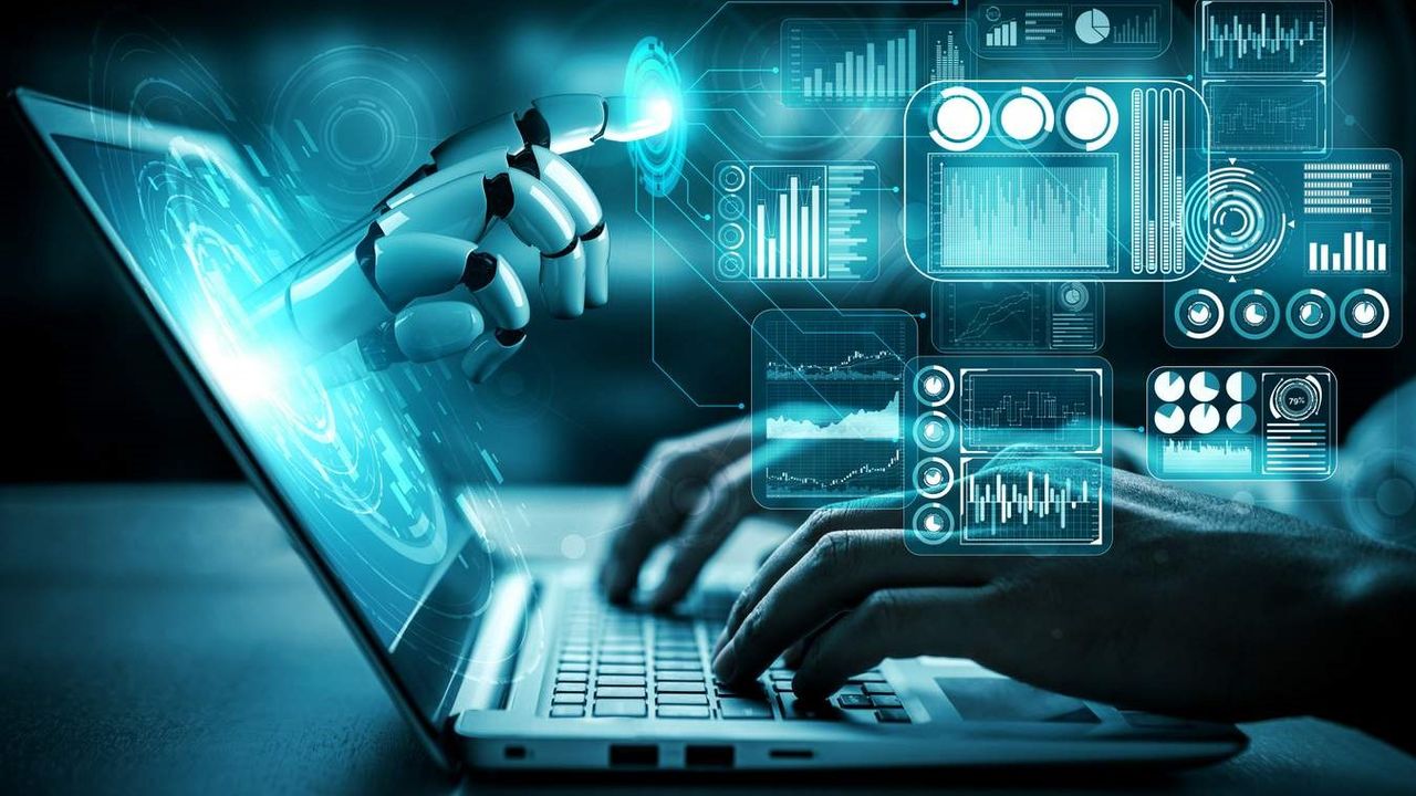 Robotic hand reaches from holographic screens above a laptop, depicting AI and data analytics.