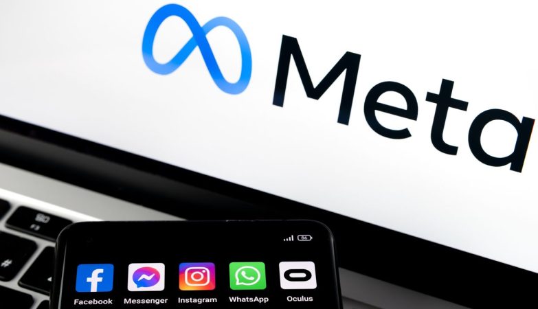 Meta logo on screen with a smartphone displaying social apps (Facebook, Messenger, Instagram, WhatsApp, Oculus)
