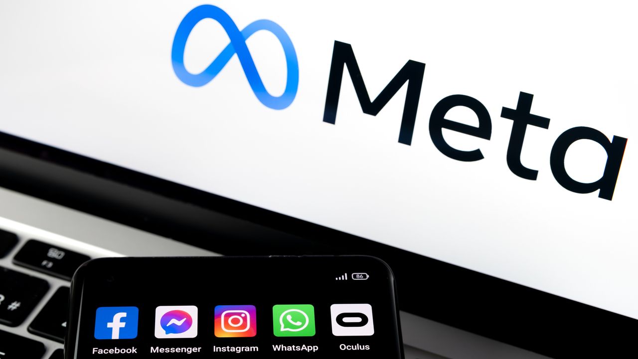 Meta logo on screen with a smartphone displaying social apps (Facebook, Messenger, Instagram, WhatsApp, Oculus)